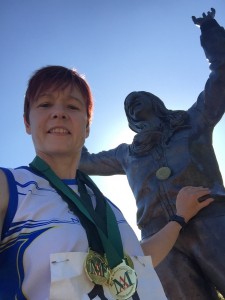 Joanne pictured with some of her athletic medals at the Mary Peter’s statue at the Belfast track named after the gold medal Olympian.