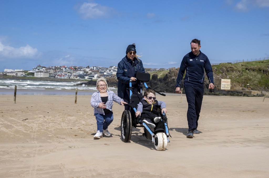 Saul Wilton 12, with his mum Jane Stewart from Portrush, Craig Connor from Sport NI and Alix Crawford Chairperson of the Mae Murray Foundation enjoying Portstewart Stand thanks to the beach mobility chair